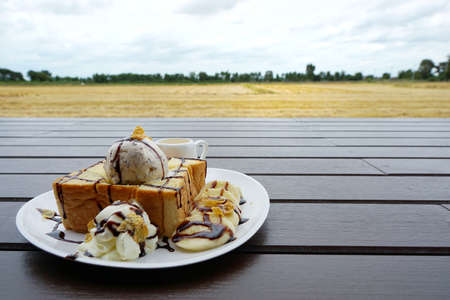Close up of honey toast with ice cream, chocolate, whip cream and cereal topped with honey on the...