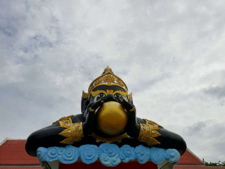 Looking up of big phra rahu on blue sky as a background in temple at Thailand, The statue pose is...