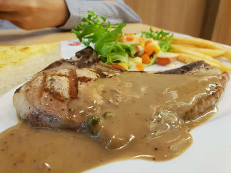 Top view of grilled Pork shop steak with french fries and salad vegetable in white plate,  Copy...