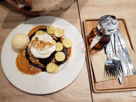 Top view of honey toast with ice cream, vanilla, banana sliced, whip cream and and honey on white plate on the wooden table, Honey toast set for Couplesの写真素材