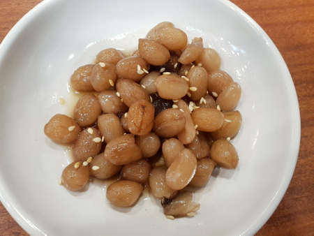 Korean food style, Top view of stir fried peanut topped with sesame seeds on white plate, side...