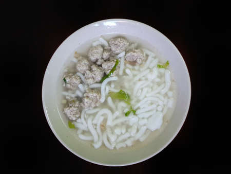 Top view of rice noodle with ground pork  and clear soup in white bowl isolated on black background,...