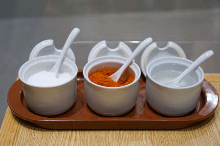 Seasoning container set for noodle to consist of cayenne pepper, sugar and vinegar on wooden table in restaurant, Thai food style, selective focusの写真素材