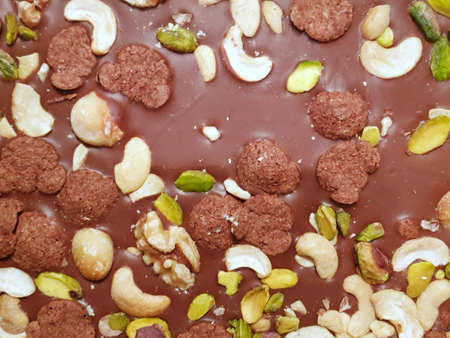 blurred image of chocolate bar with almonds, raisins, nut and grains as a background, Ready to eat,...