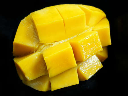 Top view of fresh yellow mango slice isolated on black background, ready to eat or making drinks