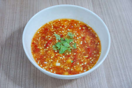 Thai food style, Top view of spicy seafood dipping sauce sprinkled with coriander slice in white bowl on wooden tableの写真素材
