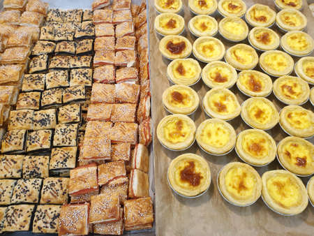 Top view of sweet braided puff pastry and mini tarts as a background for sale in the supermarket or cafe, ready to eat or serveの写真素材