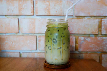 Selective focus of iced green tea in glass on wooden table in cafÃ© restaurant, Summer drink,...