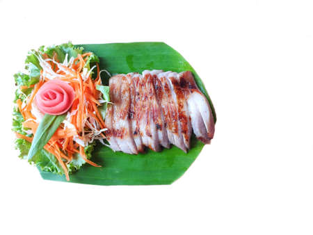 Selective focus of grilled Pork slice with mixed vegetable salad on banana leaf isolated on white background, ready for eat or serveの写真素材