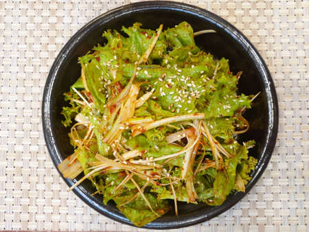 Top view of Korean lettuce pickle with sesame in black plate on the wooden table, Kimchi is korea traditional, Space for text in template, ready to eat or serveの写真素材