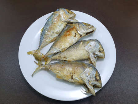 Top view of fried mackerel on white plate isolated on wooden background, Ready to eat or serveの写真素材