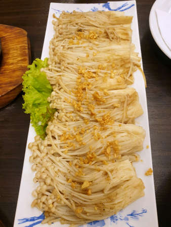 Top view of Stir fried Golden Mushroom or Enokitake with butter on white plate (Flammulina velutipes, Winter Mushroom), Verticalの写真素材