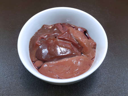 Top view of raw pork liver in white bowl isolated on wooden table as a background, Ready to cooking,...