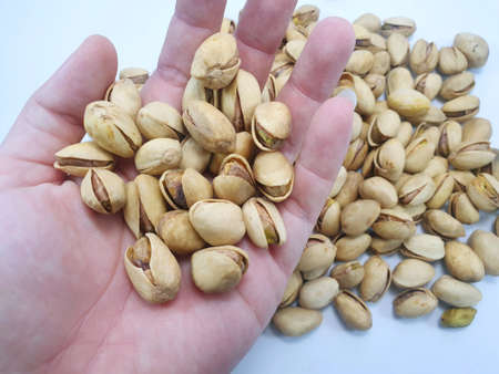 Pistachios nuts in hand on a white background close up