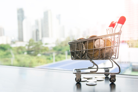 A cart model carry money coins with high tower in city as background, concept idea for business, market, financial.の写真素材