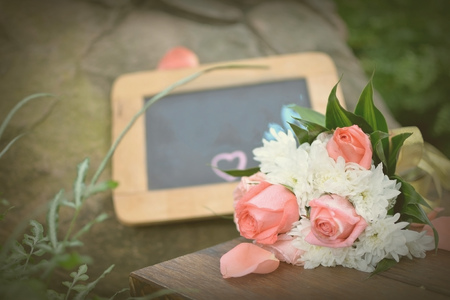 Beautiful pink roses bouquet putting on wooden table near with blackboard for wedding concept in vintage style.の写真素材