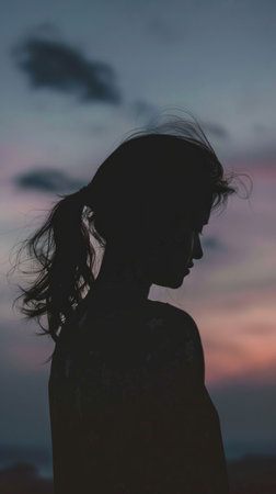 Silhouette of a woman with her hair blowing in the wind.の素材