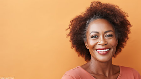 A mature African woman with a radiant smile against a warm, orange background.の素材