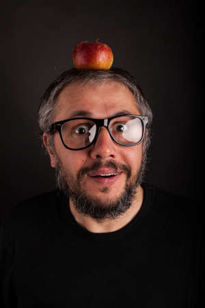 Old Man with beard and big nerd glasses with apple on head is surprisedの写真素材