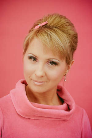 Closeup portrait of young beautiful women styled in pink 50s pin-up style. Pink seamless background.