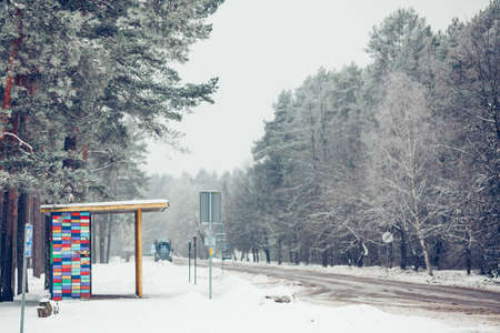 empty bus stop on cold winter afternoon, snowy road in Riga districtの写真素材