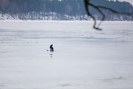 fisherman on frozen lake winter landscapeの写真素材