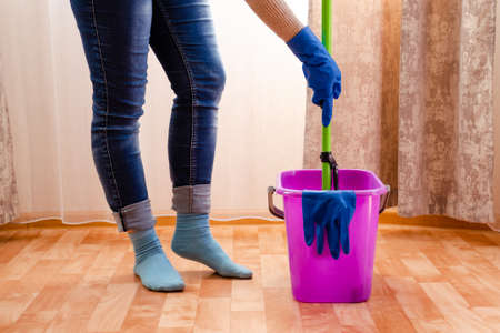 Cleaning the house with lilac bucket, blue gloves, a mop and cleaning lady's feet. home cleaning conceptの写真素材