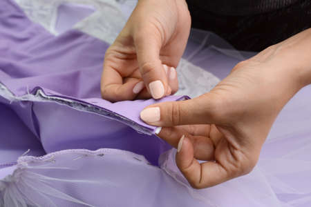 Seamstress in the atelier with a needle punches lilac fabric, small business concept, horizontal...