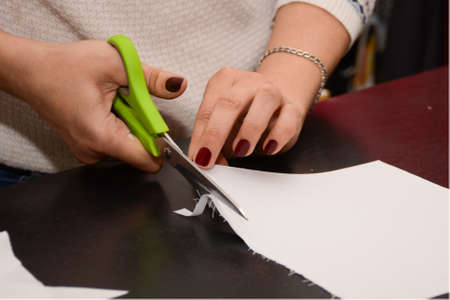 The hands of a seamstress cut white fabric with scissors. small business conceptの写真素材