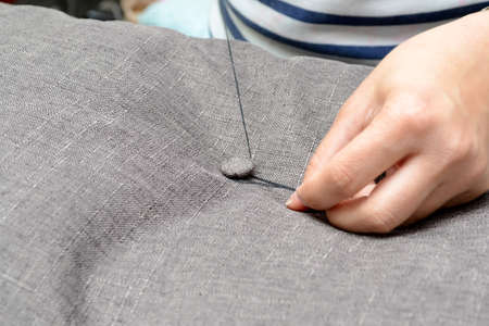 Small business concept. Woman sews a button on a gray fabric, horizontal photo.の写真素材