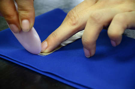 Sewing master makes handicraft of fabric. Cutting with a mark of soap on blue cloth. Trimming fabric...