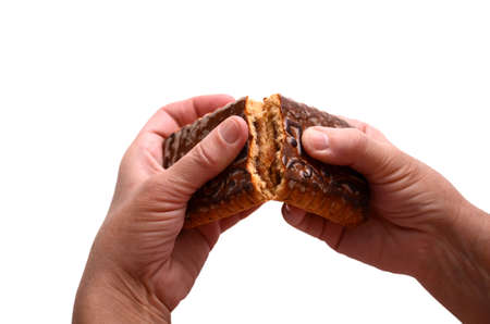 Women's hands break a big and tasty gingerbread. Fresh brown gingerbread. isolated.の写真素材