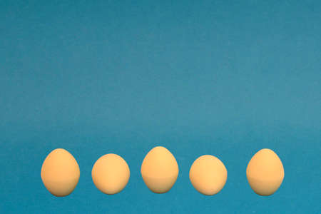 White chocolate eggs on a blue background. The eggs are lined with a line. Easter celebration, copy space.の写真素材