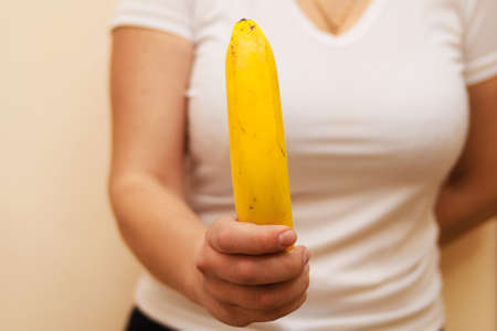 Fresh yellow banana in a female hand. Horizontal photo, concept of eating healthy and vegetarianism.の写真素材