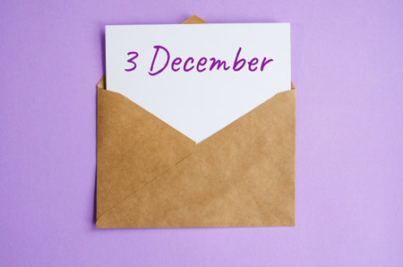 Kraft envelope with a white sheet of paper and the inscription December 3 on lilac background. Correspondence calendar and memorable date conceptの写真素材
