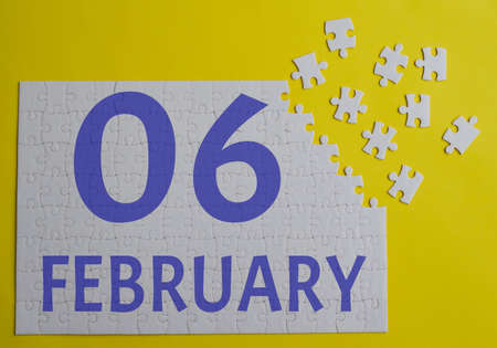 6 february calendar date on a white puzzle with separate details. Puzzle on yellow background with blue inscriptionの写真素材