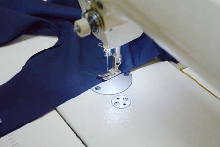 Sewing a dark blue fabric on a white sewing machine. Small business concept. selective focus.