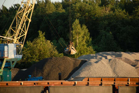 Loading and unloading large piles of sand and gravel with water crane. The concept of transportation...