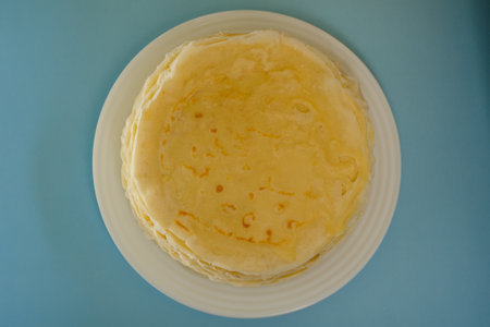 Thin pancakes are national Russian dish. Fresh dish on blue background flat lay