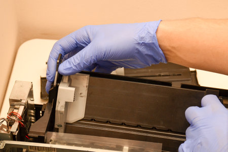 The master repairs the paper feed tray on an inkjet printer. Close-up photo about workの写真素材