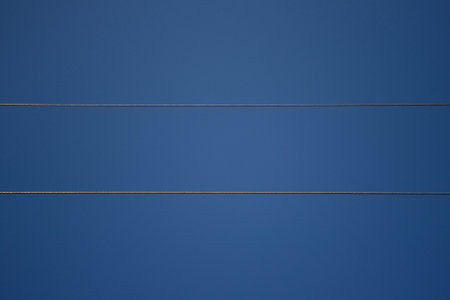 Power line wires against blue sky. Wires covered with frost, frosty winter dayの写真素材