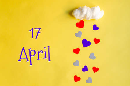 17 april day of month, colorful hearts rain from white cotton cloud on yellow background. Valentine's day, love and wedding conceptの写真素材