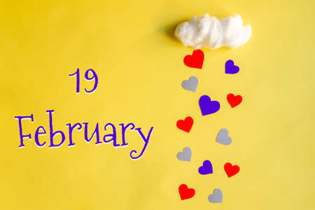 19 february day of month, colorful hearts rain from white cotton cloud on yellow background. Valentine's day, love and wedding conceptの写真素材