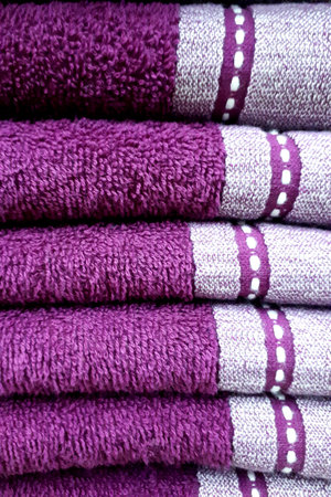 Soft terry towels of violet color with a light pattern, folded on top of each other. Terry towel texture, vertical photoの写真素材