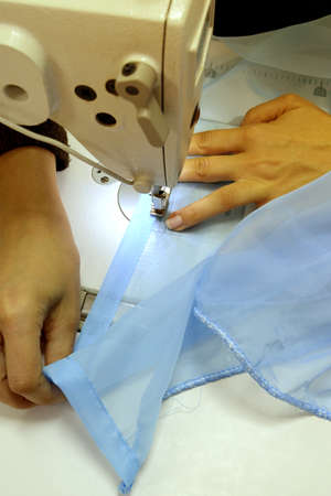 The seamstress sews on a sewing machine, fulfills the order. Scribbles a bluecloth. Sewing curtains....