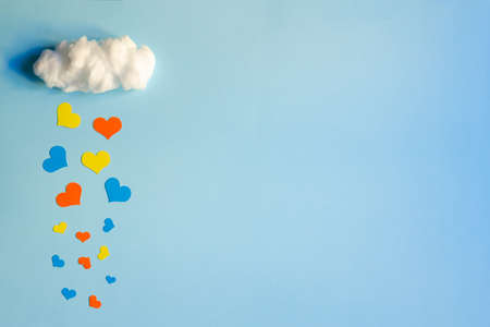 Colorful hearts rain from white cotton cloud on a blue background, with copy space. Valentine's day, love and wedding concept, flat layの写真素材