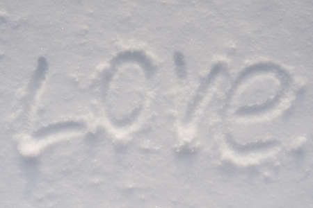 The inscription love written on white snow. Flat lay, romance conceptの写真素材