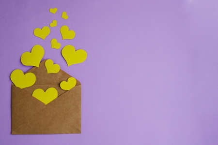 Brown envelope with yellow hearts on lilac background with copy space. Flat lay, valentine's day conceptの写真素材