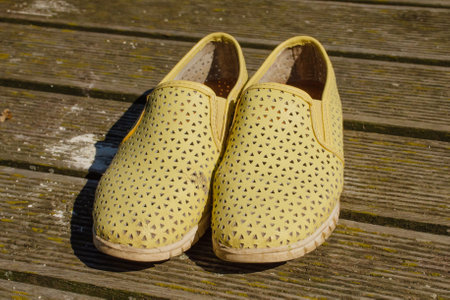 Old yellow female loafers on wooden background. Horizontal photo of work shoes