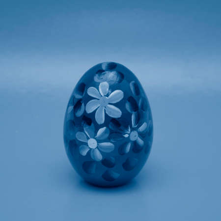 Handmade painted easter egg. Toning photo in classic blue. Top view of easter composition of tinted eggs in bright juicy colors.の写真素材